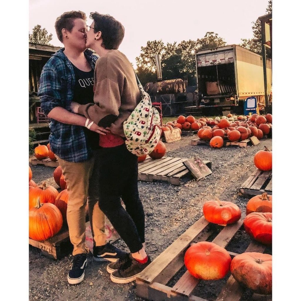 two women kissing among pumpkins