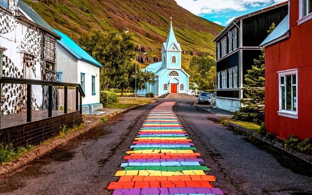 Street with painted rainbow on the ground and blue church