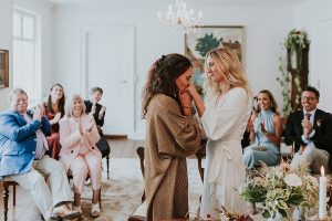 Two brides kissing at wedding ceremony