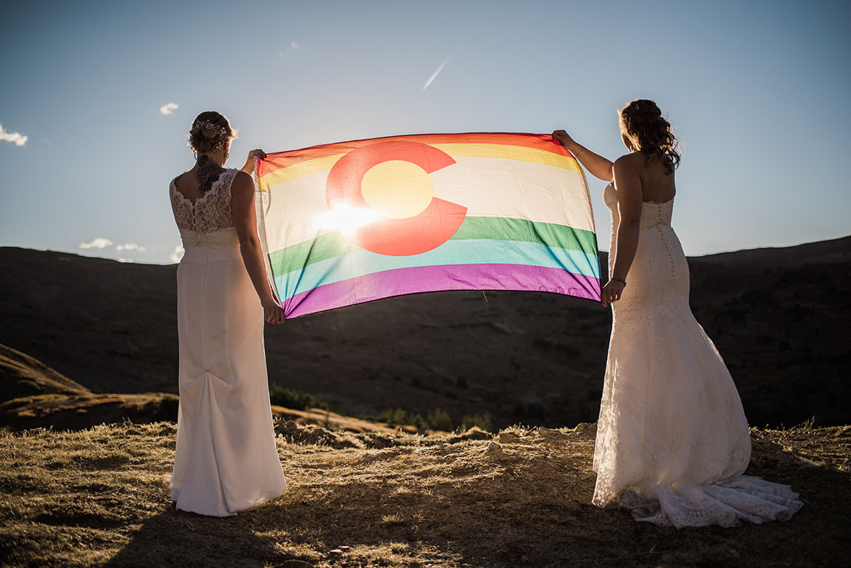 Two brides with rainbow flag