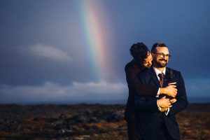 two grooms and rainbow behind them